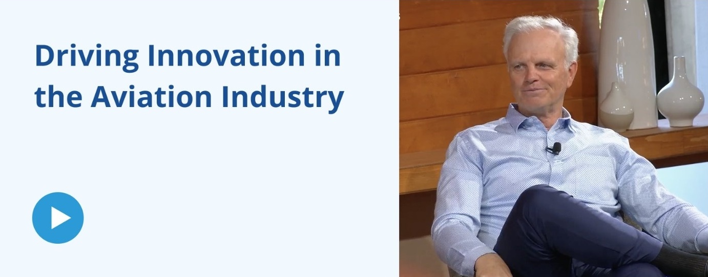 A promotional graphic or video thumbnail. The left side features a light blue background with the dark blue text "Driving Innovation in the Aviation Industry" above a circular play button icon. The right side contains a photograph of a smiling, white-haired man sitting casually in a chair, wearing a light blue patterned button-down shirt and dark pants.