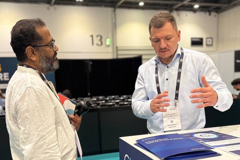 Close up of a GP Solutions representative actively explaining something to an attendee at their tech booth.