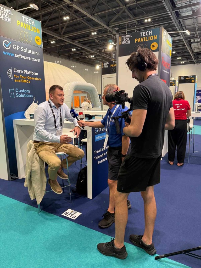 Sergey Zubekhin sitting at the GP Solutions booth is being interviewed on camera by a media team at the exhibition.