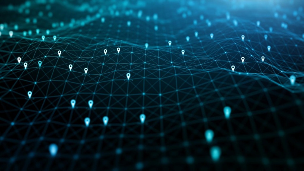 Eine konzeptuelle digitale Illustration zeigt eine blau leuchtende Netz- oder „Gitter"-Landschaft. Zahlreiche weiße Standortsymbole sind über die Gipfel und Täler der digitalen Terrainlandschaft verstreut und repräsentieren Datenpunkte, Reiseziele oder ein globales, durch Technologie verbundenes Netzwerk.